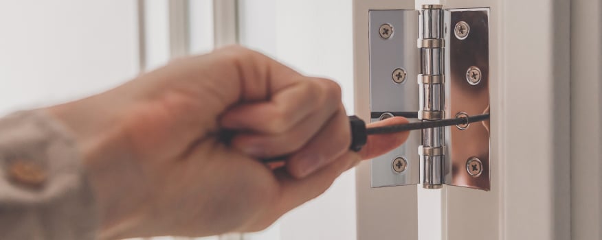 Using a screw driver to tighten a door hinge