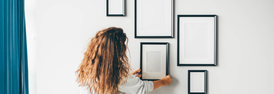 woman hanging pictures on gallery wall