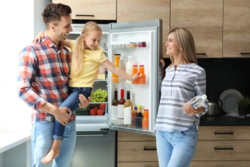 family standing in front of open fridge