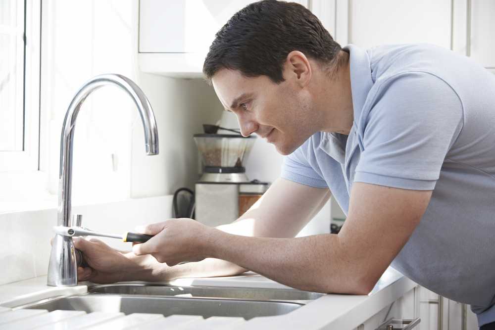 man tightening tap with wrench